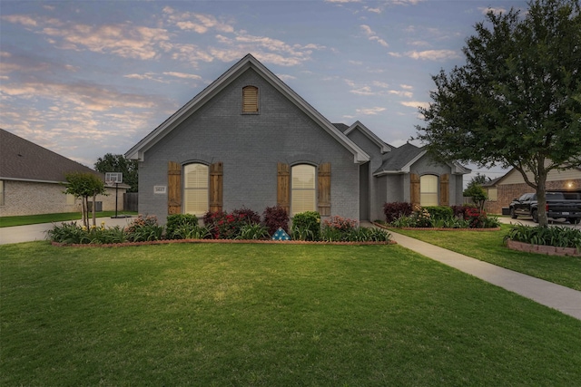 view of front of home with brick siding and a yard