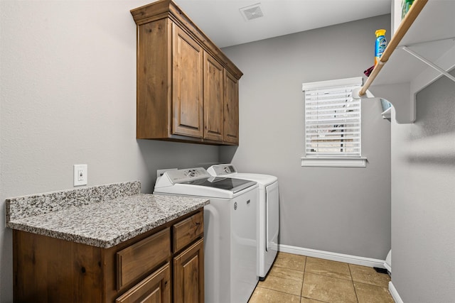 laundry room with light tile patterned flooring, separate washer and dryer, visible vents, baseboards, and cabinet space