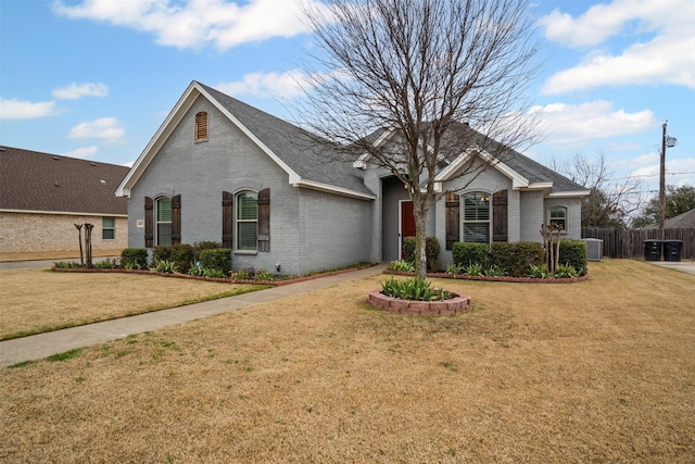 view of front of house featuring brick siding, fence, a front lawn, and central air condition unit