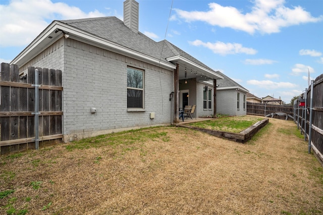 back of house with a patio, brick siding, a lawn, and a fenced backyard