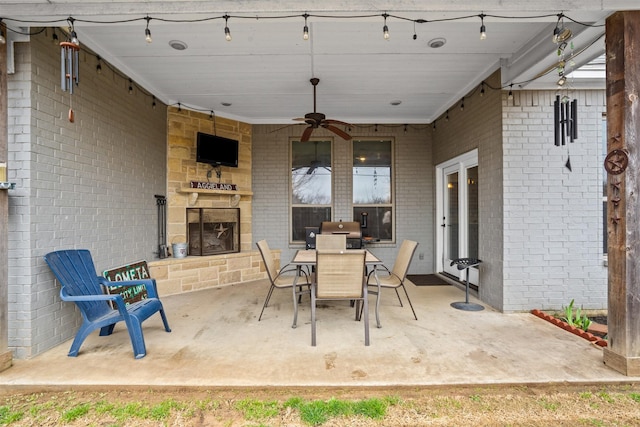 view of patio featuring outdoor dining area, ceiling fan, and an outdoor stone fireplace