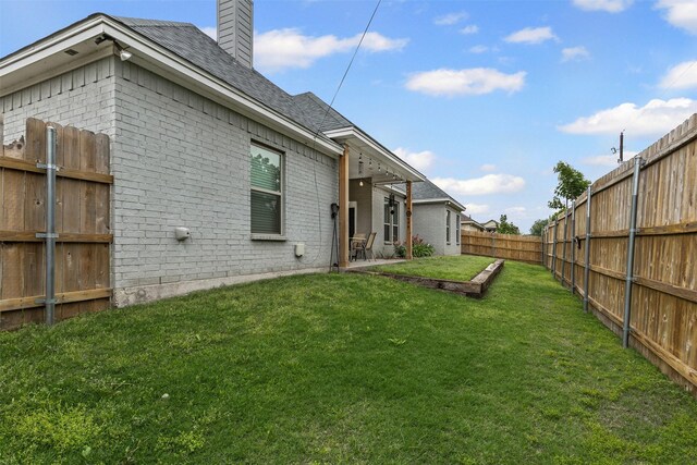back of house with a lawn, brick siding, a chimney, and a fenced backyard