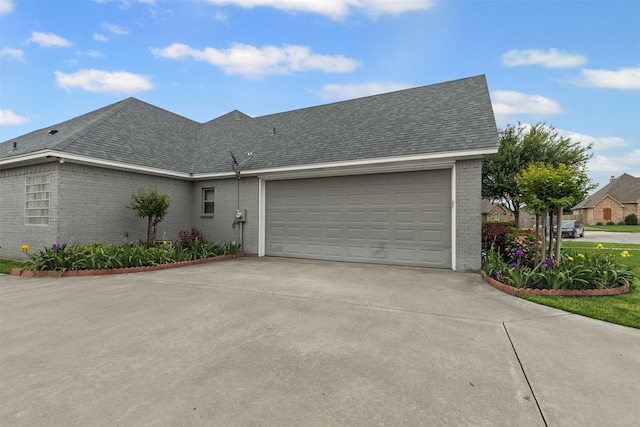 single story home featuring brick siding, an attached garage, roof with shingles, and concrete driveway