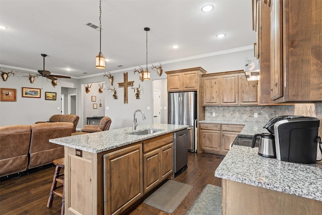 kitchen with dark wood-style floors, stainless steel appliances, backsplash, open floor plan, and a sink