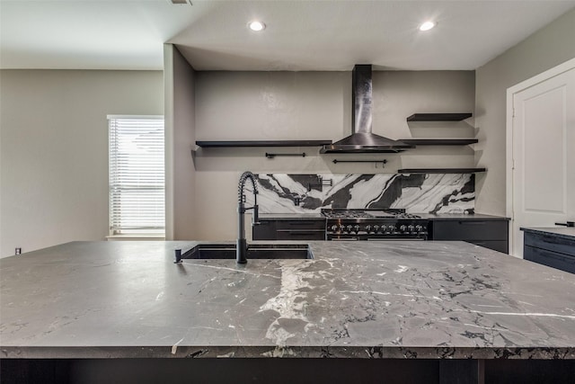 kitchen featuring tasteful backsplash, recessed lighting, a sink, wall chimney range hood, and high end stove