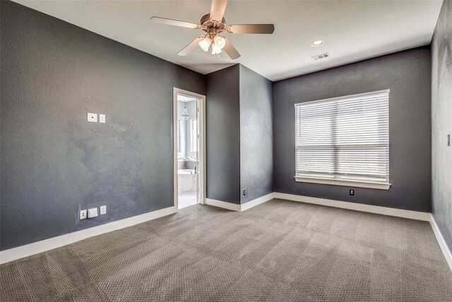 carpeted empty room with visible vents, baseboards, a ceiling fan, and a textured wall