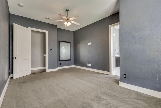 carpeted empty room with ceiling fan, visible vents, and baseboards