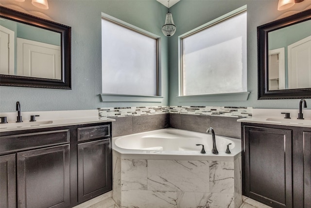 full bathroom featuring marble finish floor, a garden tub, and vanity