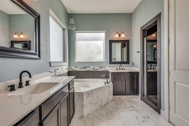 bathroom with marble finish floor, a sink, and a bath