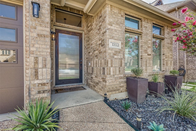 doorway to property with a garage and brick siding