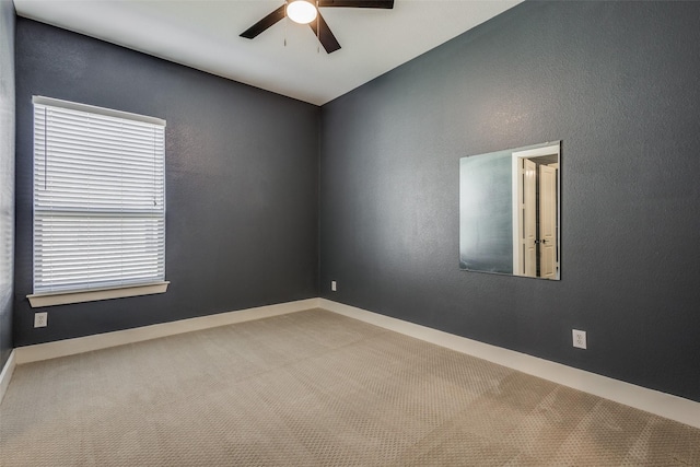 empty room with carpet floors, a textured wall, ceiling fan, and baseboards