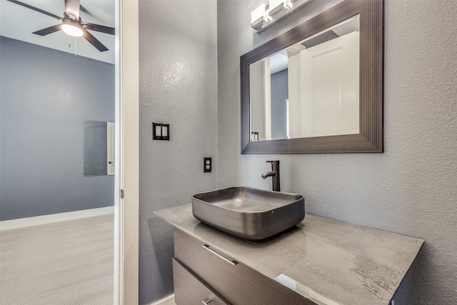 bathroom featuring baseboards, a textured wall, vanity, and a ceiling fan