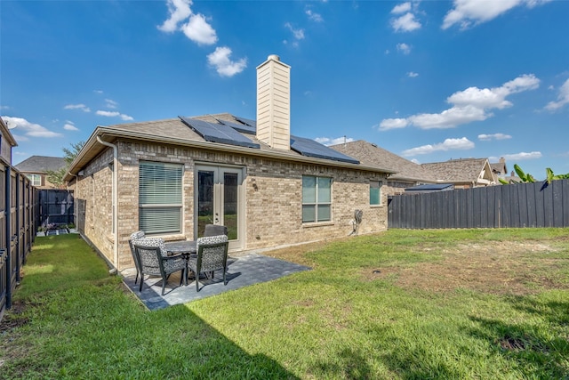 back of house with a lawn, a fenced backyard, a chimney, a patio area, and brick siding