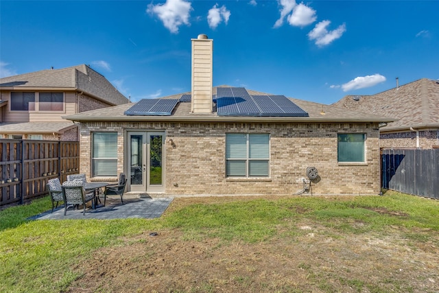 rear view of property featuring a patio, a yard, a chimney, and a fenced backyard