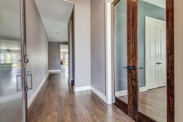 corridor featuring wood-type flooring and baseboards