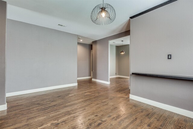 spare room with baseboards, visible vents, and wood finished floors