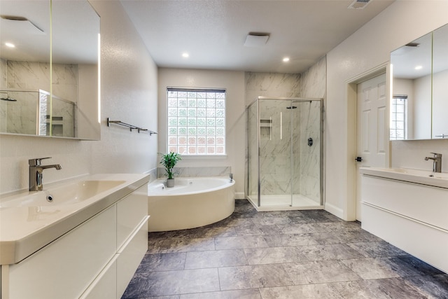 full bath featuring two vanities, a sink, a marble finish shower, and a bath