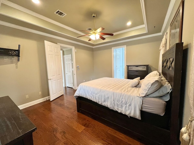 bedroom with a tray ceiling, dark wood-type flooring, visible vents, and baseboards