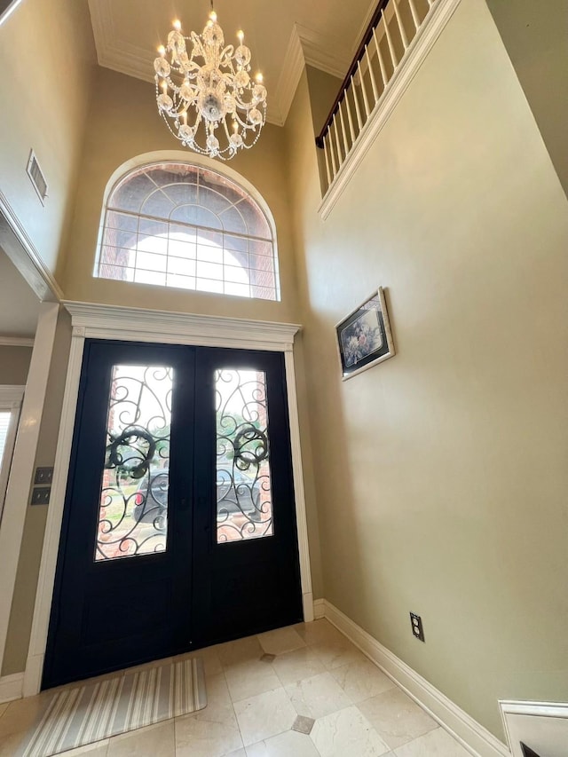 entryway with baseboards, a high ceiling, crown molding, french doors, and a notable chandelier