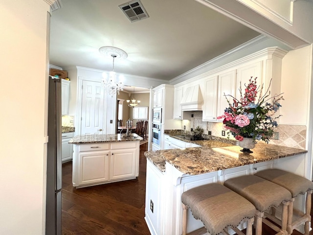 kitchen featuring stone countertops, visible vents, dark wood-style floors, appliances with stainless steel finishes, and an inviting chandelier