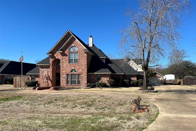 traditional-style home featuring concrete driveway, brick siding, and a chimney