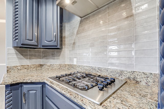 kitchen featuring blue cabinetry, stainless steel gas cooktop, light stone counters, and tasteful backsplash