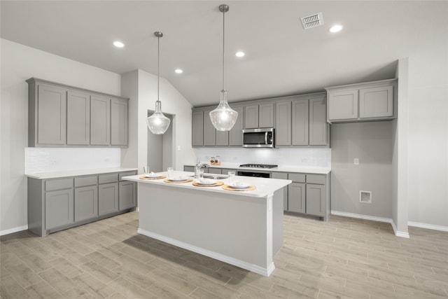 kitchen with visible vents, gray cabinets, a sink, stove, and stainless steel microwave