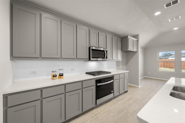 kitchen with stainless steel appliances, tasteful backsplash, visible vents, and gray cabinets