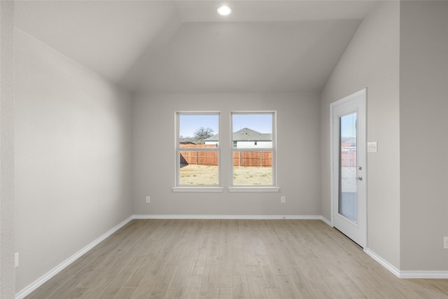 empty room with baseboards, lofted ceiling, and light wood-style flooring