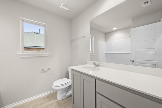 full bath featuring vanity, wood finished floors, visible vents, baseboards, and toilet