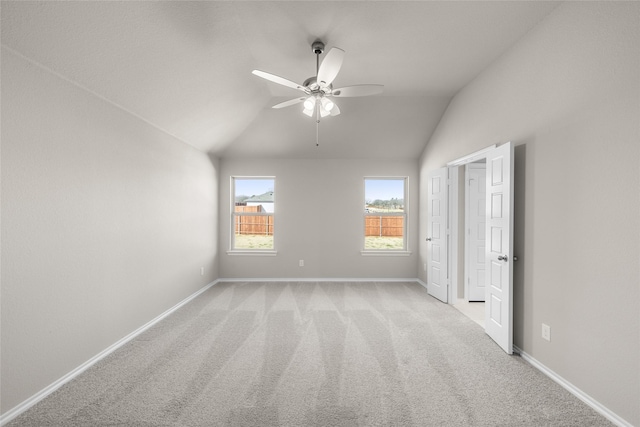 spare room with light colored carpet, baseboards, a ceiling fan, and vaulted ceiling