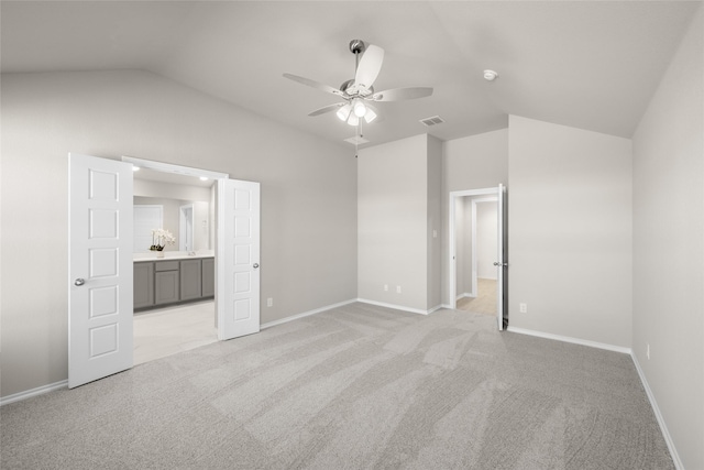 unfurnished bedroom with visible vents, light carpet, ensuite bath, baseboards, and vaulted ceiling