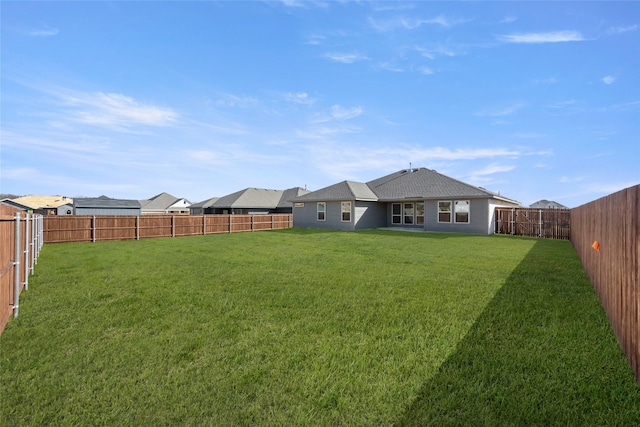 rear view of property featuring a lawn and a fenced backyard