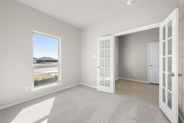 empty room with french doors, baseboards, and carpet