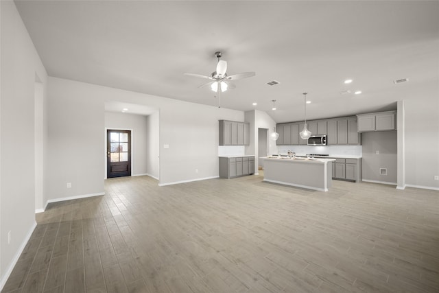 unfurnished living room featuring visible vents, baseboards, ceiling fan, and light wood finished floors