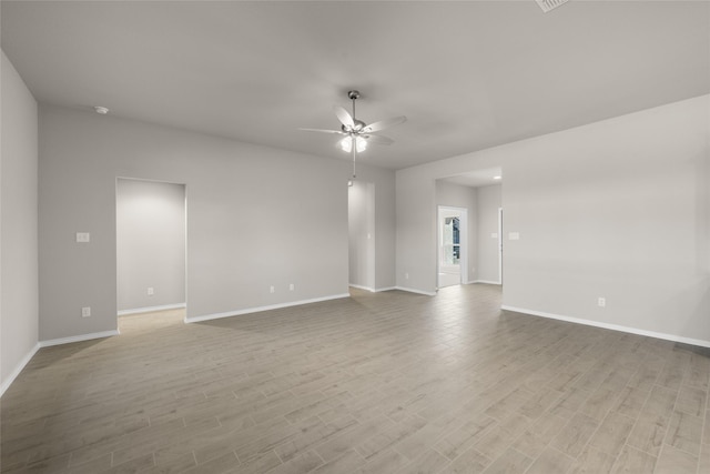 empty room featuring light wood-style flooring, a ceiling fan, and baseboards