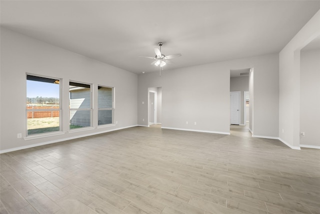 empty room featuring baseboards, ceiling fan, and wood finished floors