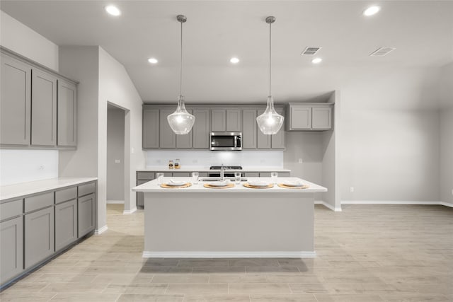 kitchen featuring a sink, stainless steel microwave, gray cabinetry, and visible vents