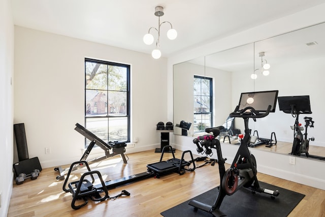 exercise room with visible vents, baseboards, and light wood finished floors