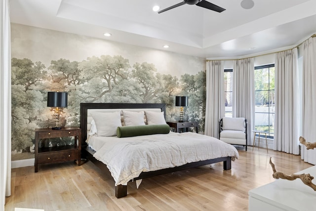 bedroom with wallpapered walls, ceiling fan, a tray ceiling, recessed lighting, and wood finished floors