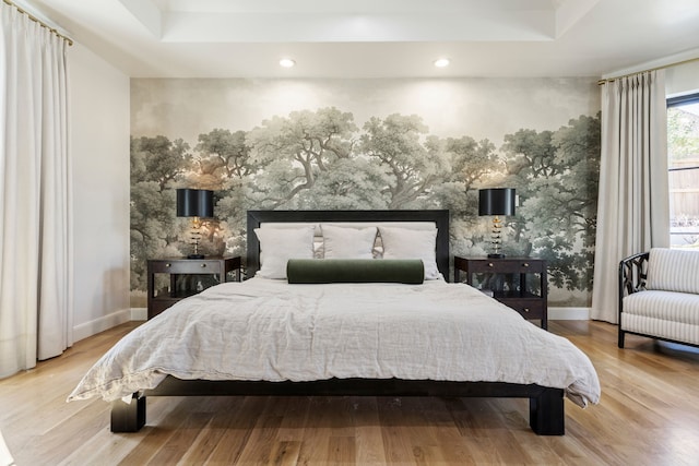 bedroom featuring a tray ceiling, wood finished floors, and baseboards