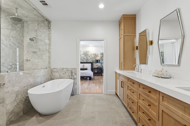 ensuite bathroom featuring a marble finish shower, visible vents, double vanity, a freestanding tub, and a sink