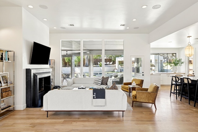 living room featuring recessed lighting, light wood-type flooring, visible vents, and a fireplace