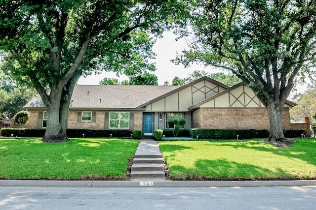 view of front of property with a front yard, brick siding, and roof with shingles