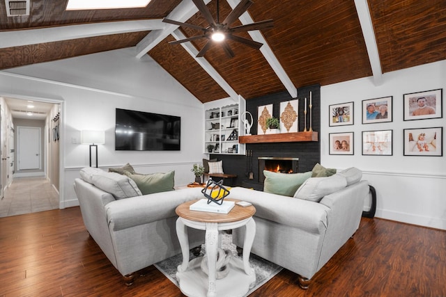 living area with a brick fireplace, visible vents, wood finished floors, and beamed ceiling