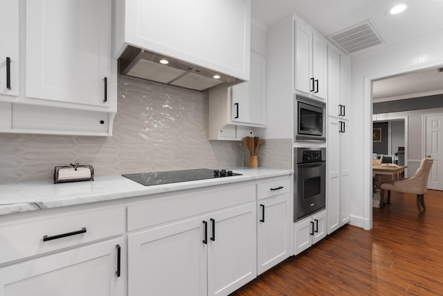 kitchen featuring stainless steel appliances, premium range hood, visible vents, white cabinetry, and tasteful backsplash