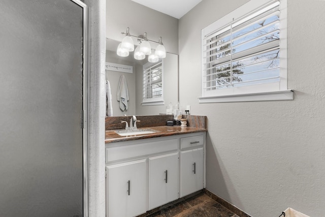 bathroom with a shower with shower door, a textured wall, baseboards, and vanity