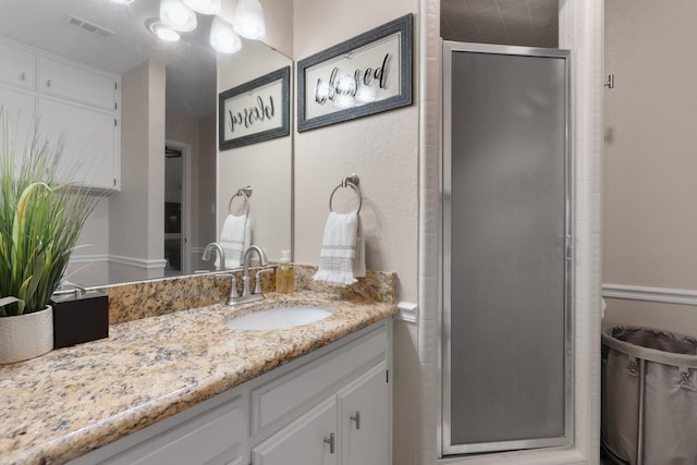 bathroom with vanity, a shower stall, and visible vents