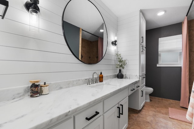 bathroom featuring toilet, tile patterned floors, wooden walls, and vanity