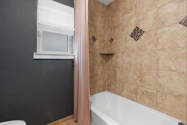 bathroom with shower / bathtub combination with curtain and baseboards